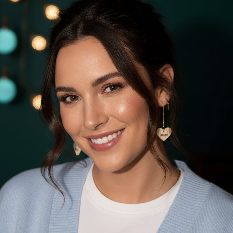 Woman wearing heart-shaped earrings with &