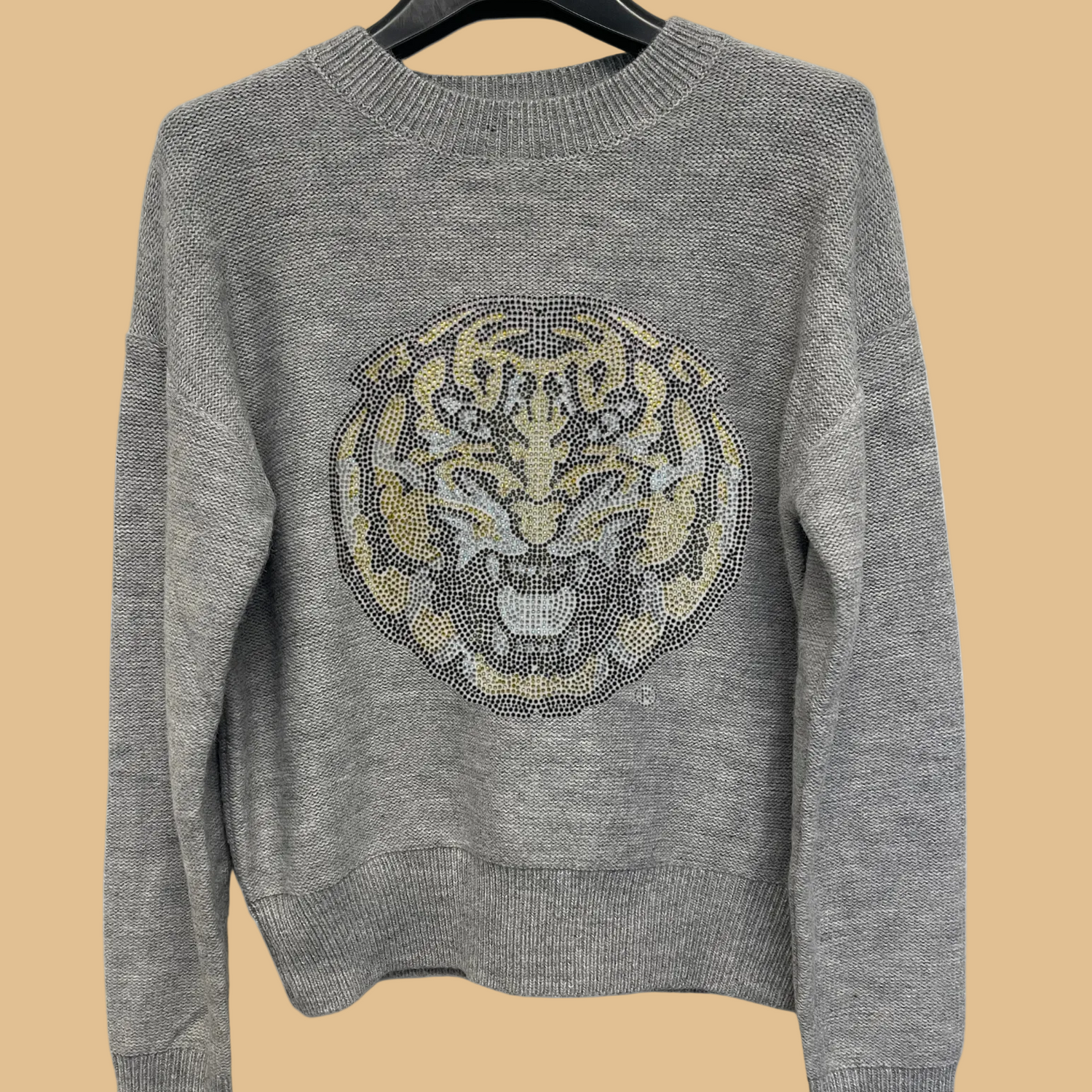 Gray sweater with a tiger emblem on a hanger against a white background