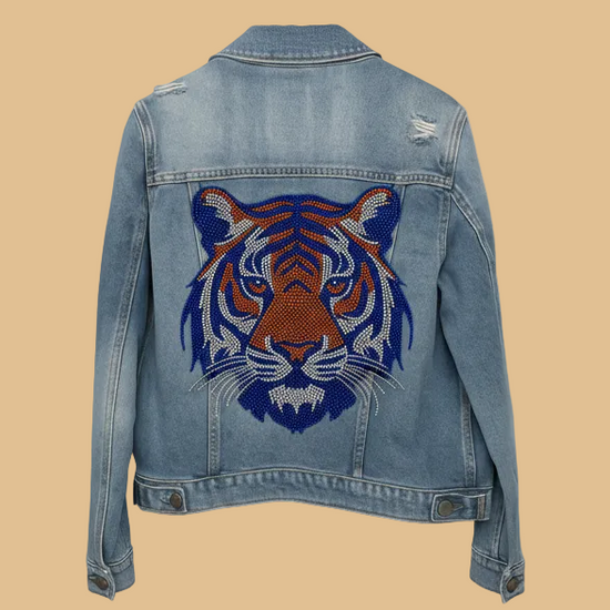 Denim jacket with a tiger face design on the back against a white background