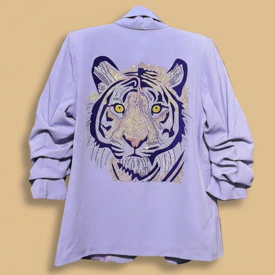 Light purple shirt with a tiger design on a rack against a dark background