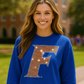 Woman wearing a blue sweatshirt with a large &