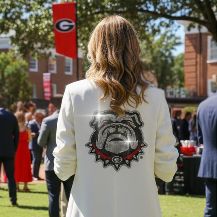 Person wearing a white blazer with a bulldog logo at an outdoor event.