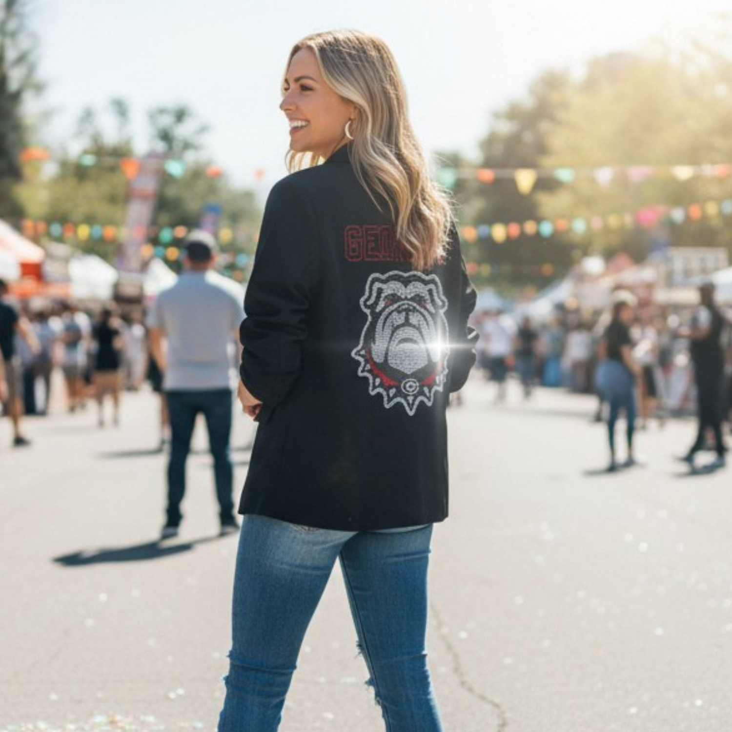 Woman wearing a black jacket with a logo, standing outdoors at a festival.