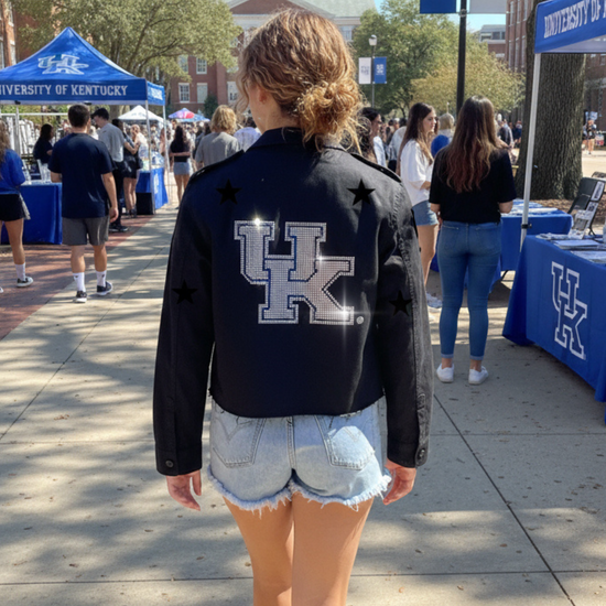 Person wearing a black jacket with a large &