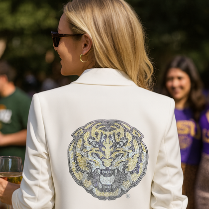 Person wearing a white blazer with a tiger emblem at an outdoor event.
