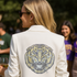 Person wearing a white blazer with a tiger emblem at an outdoor event.