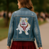 Person wearing a denim jacket with a bulldog design and red skirt outdoors.