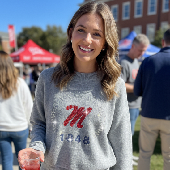 Woman wearing a gray sweater with a red and blue &