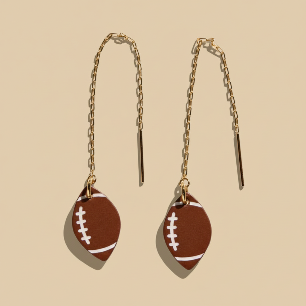 Football-shaped earrings with gold chains on a white background
