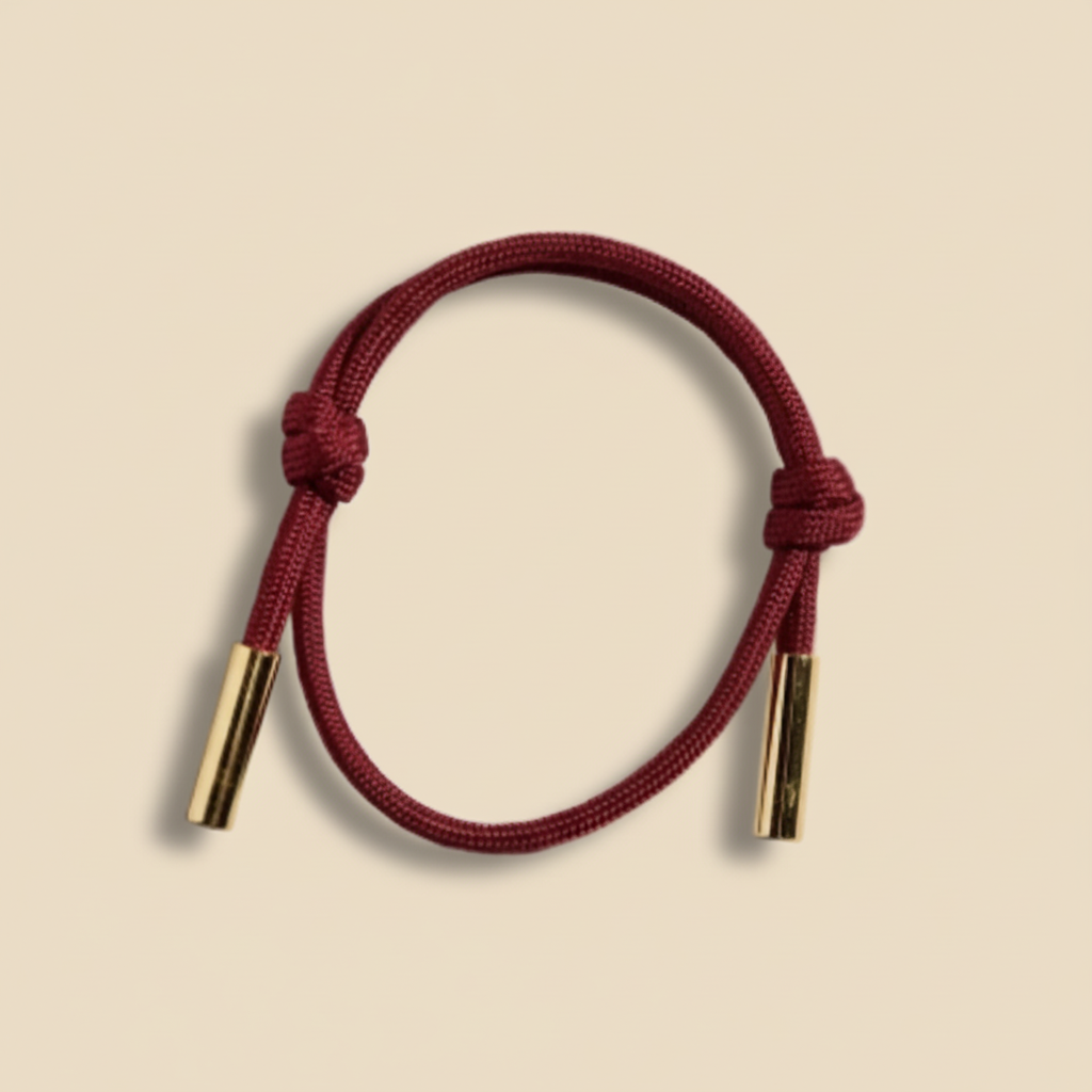 Red cord bracelet with gold ends on a white background