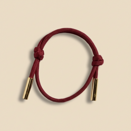 Red cord bracelet with gold ends on a white background