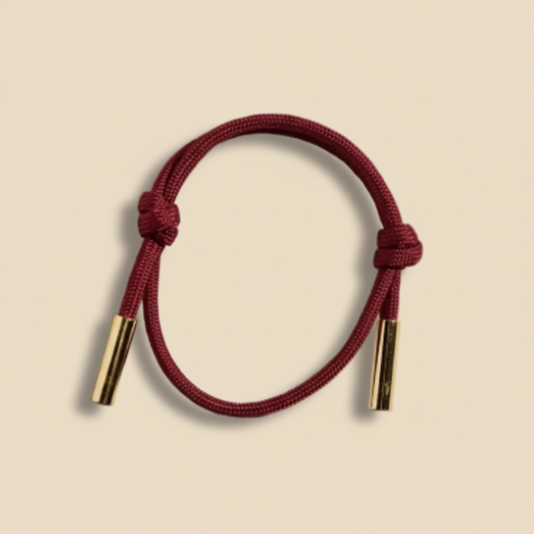 Red cord bracelet with gold ends on a white background