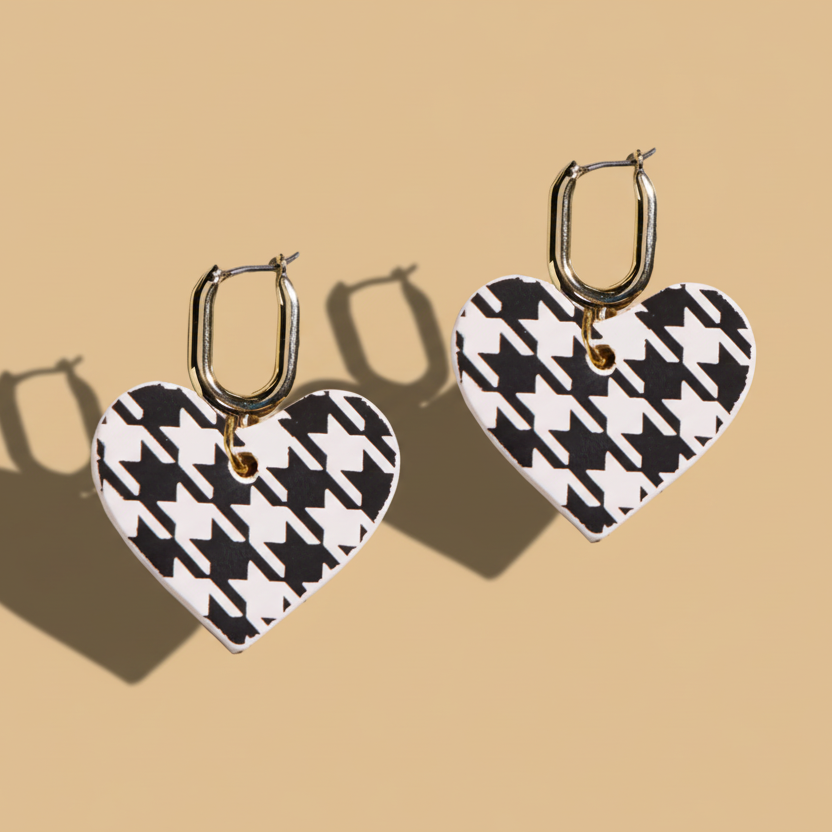 Heart-shaped earrings with black and white houndstooth pattern on a beige background