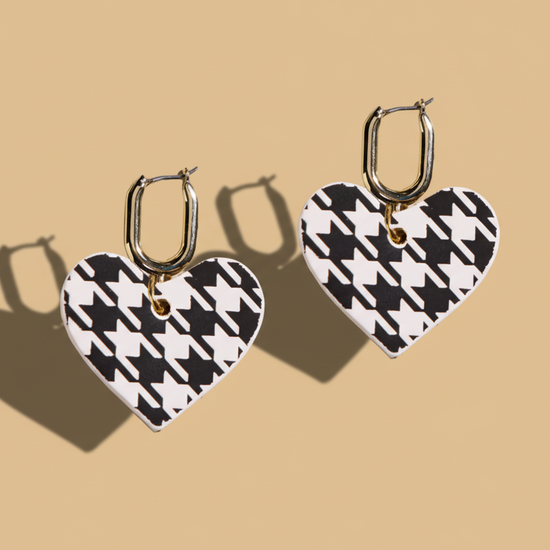 Heart-shaped earrings with black and white houndstooth pattern on a beige background