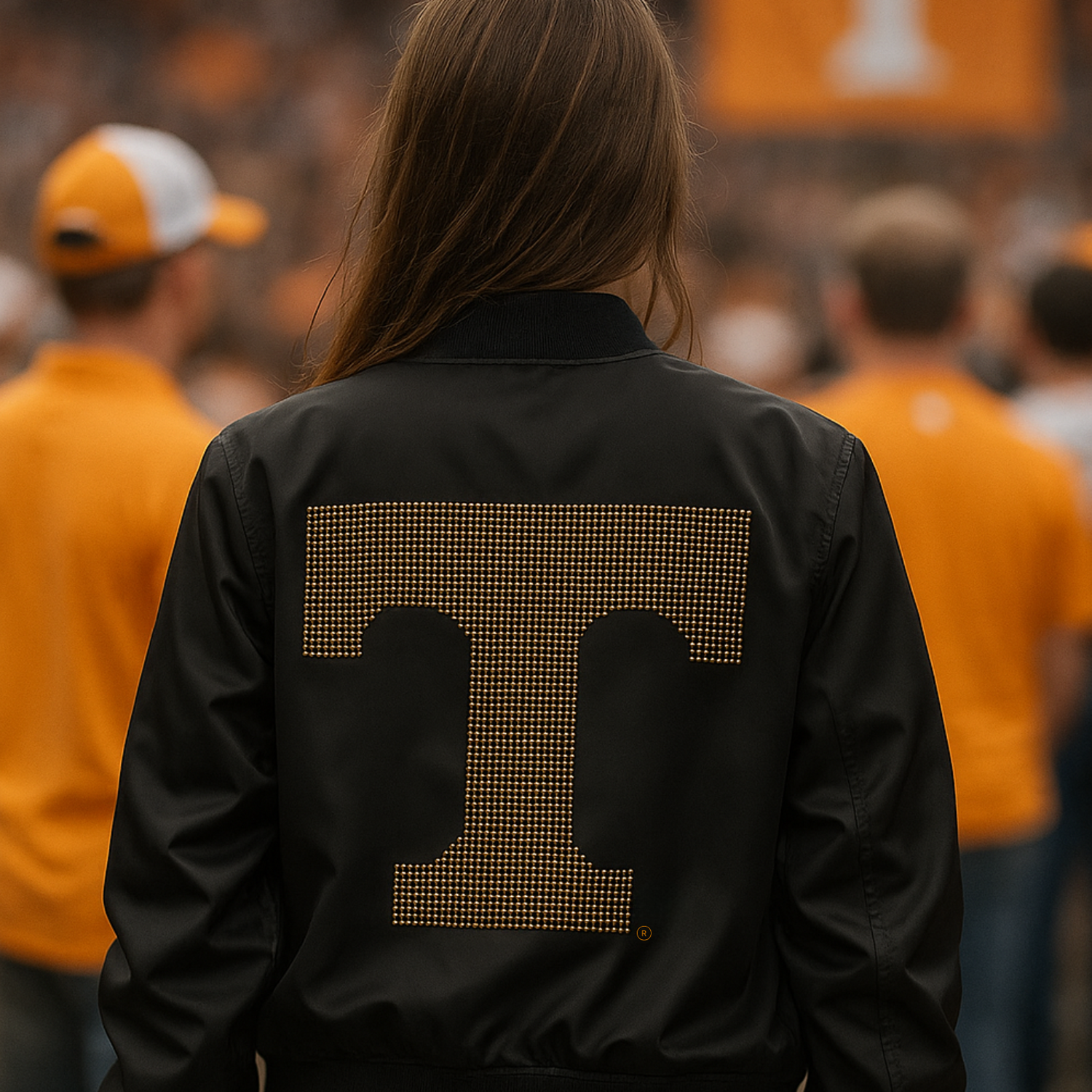 Person wearing a black jacket with a gold &