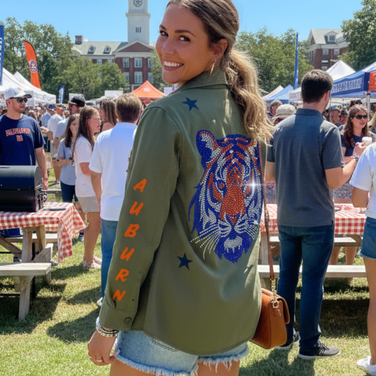 Woman wearing an Auburn University jacket with a tiger design at an outdoor event.