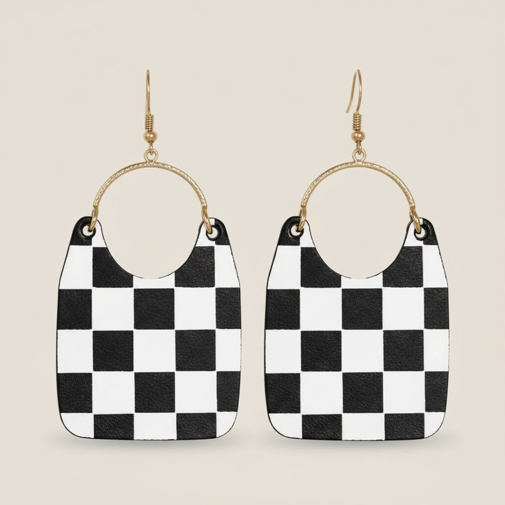 Black and white checkered earrings with gold hoop accents on a beige background