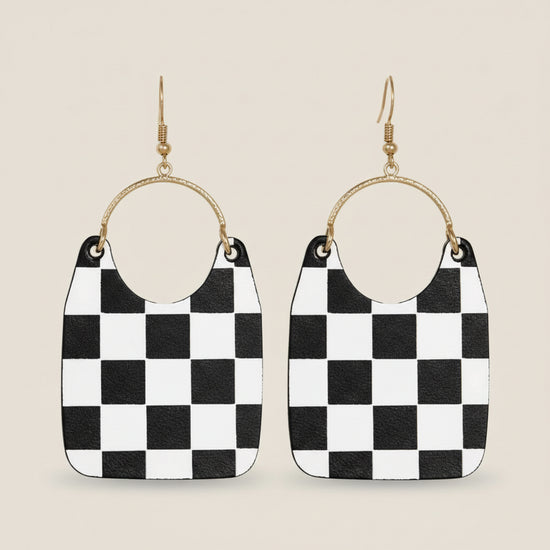 Black and white checkered earrings with gold hoop accents on a beige background