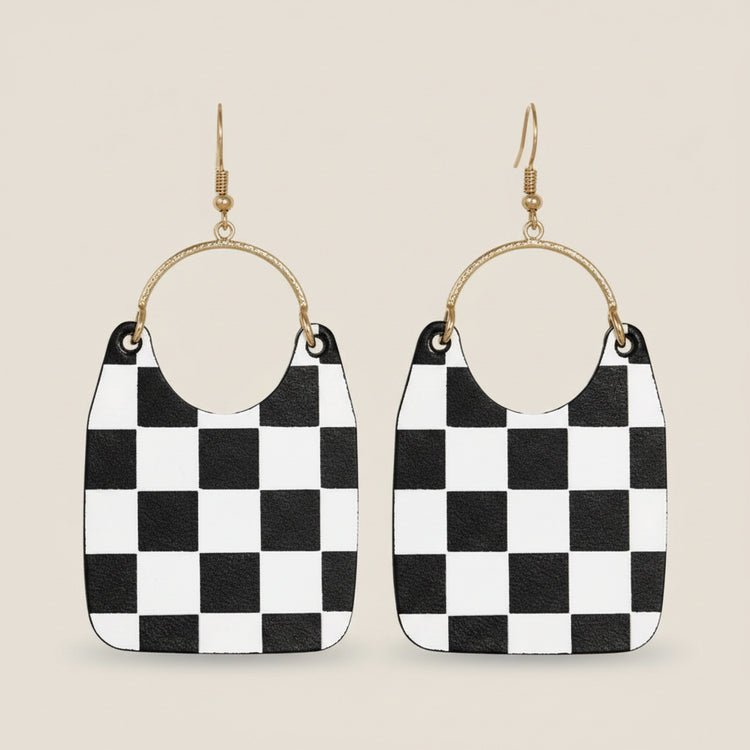 Black and white checkered earrings with gold hoop accents on a beige background