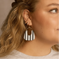 Close-up of a woman wearing a black and white striped earring against a neutral background