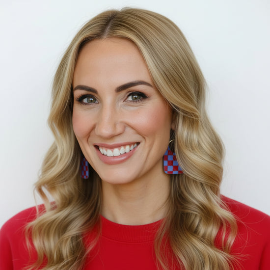 Woman wearing red sweater and colorful earrings against a white background