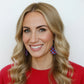 Woman wearing red sweater and colorful earrings against a white background