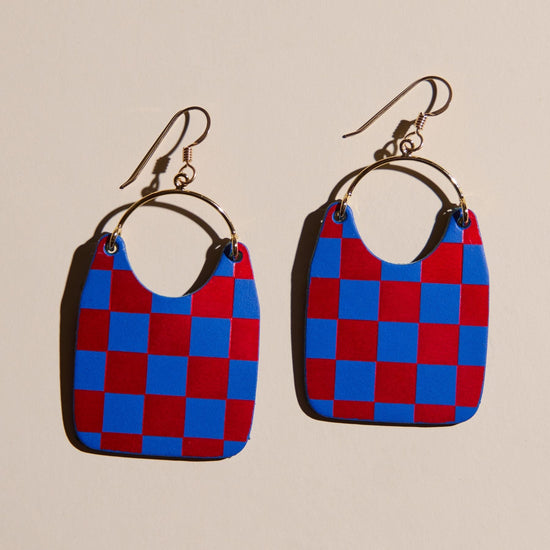 Red and blue checkered earrings on a beige background