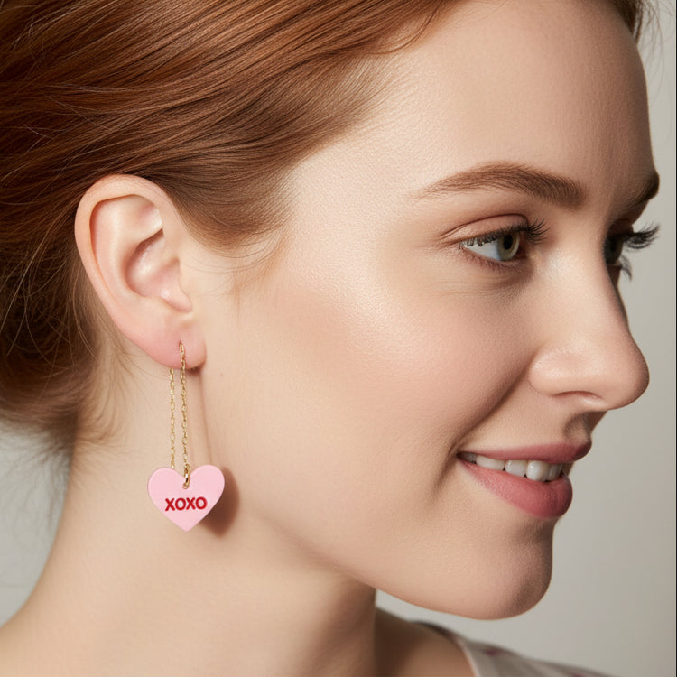Close-up of a person wearing pink heart-shaped earrings with &