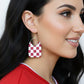 Close-up of a woman wearing a checkered earring with a blurred background