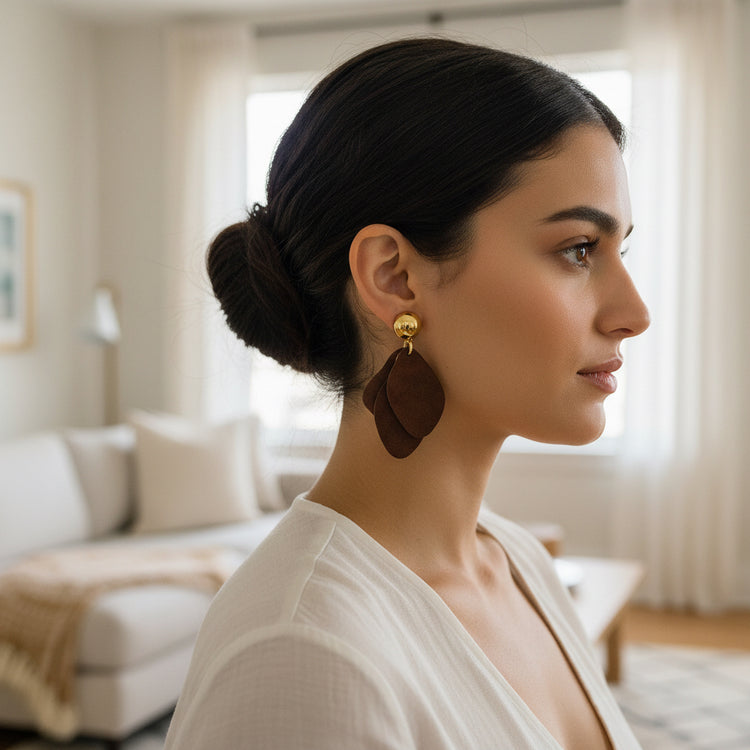 Brown suede earrings with gold accents on a beige background