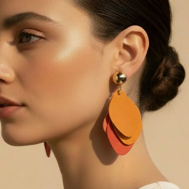 Pair of orange layered earrings on a beige background