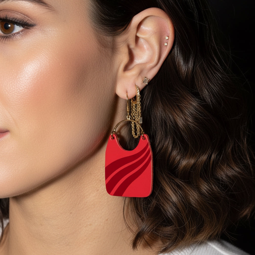 Close-up of a person wearing a red earring with a gold chain.