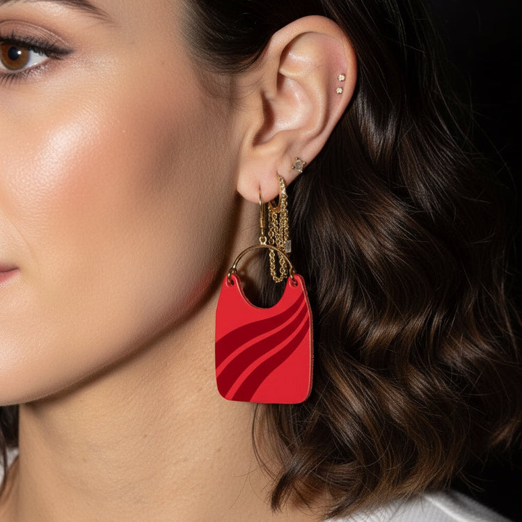 Close-up of a person wearing a red earring with a gold chain.