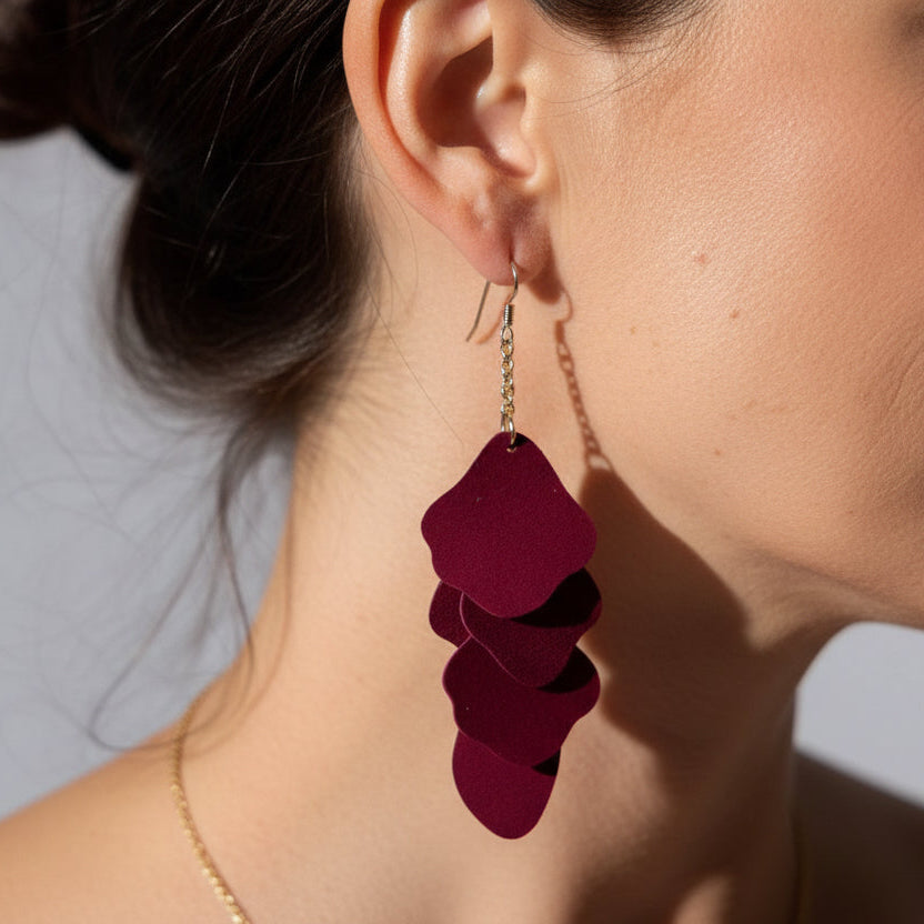 Close-up of a person wearing a burgundy layered earring.