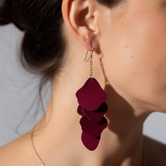Close-up of a person wearing a burgundy layered earring.