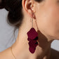 Close-up of a person wearing a burgundy layered earring.