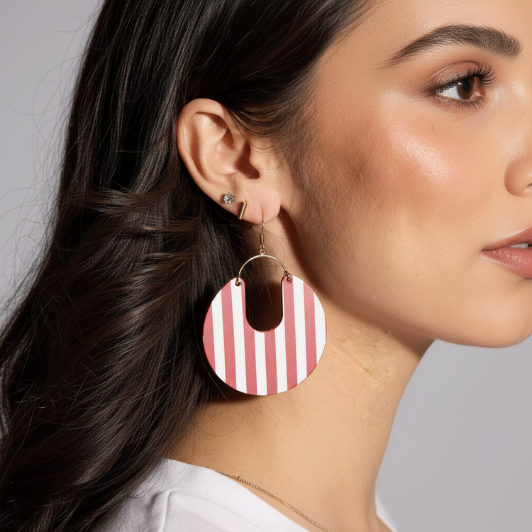 Close-up of a person wearing red and white striped earrings with a neutral background