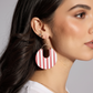 Close-up of a person wearing red and white striped earrings with a neutral background