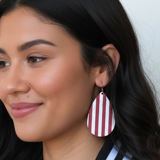 Close-up of a woman wearing pink and white striped earrings against a neutral background