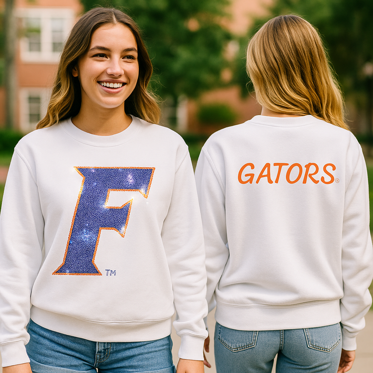 Two women wearing white sweatshirts with a large blue &