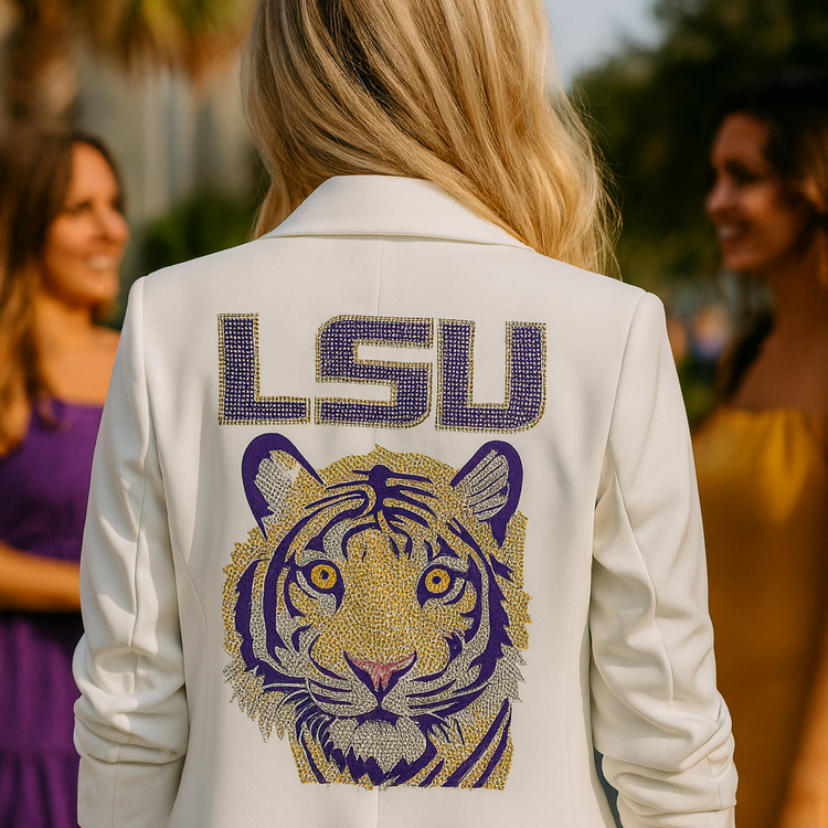 Person wearing a white blazer with LSU tiger logo, standing outdoors with blurred people in the background.