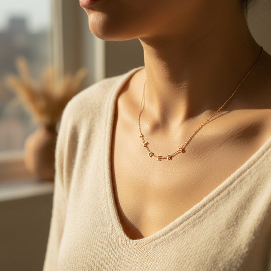 Gold necklace with letter pendants on a beige background