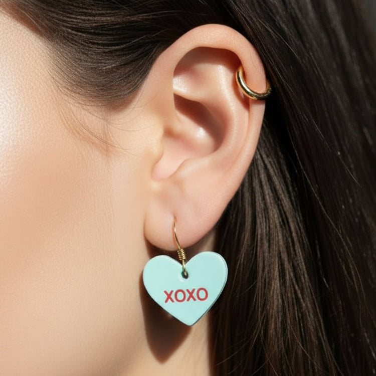 Close-up of an ear wearing a turquoise heart-shaped earring with &