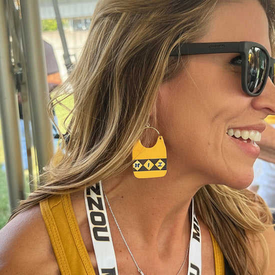 Woman wearing sunglasses and a yellow tank top with a &