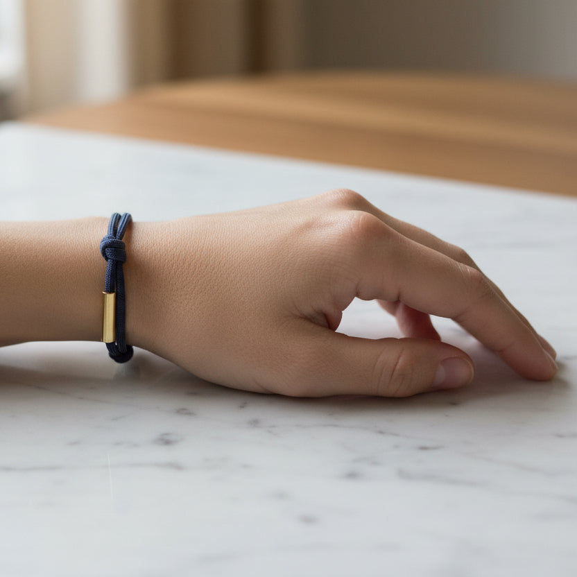 Navy blue braided bracelet with gold metal clasps on a beige background