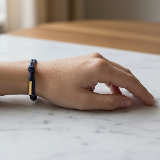 Navy blue braided bracelet with gold metal clasps on a beige background