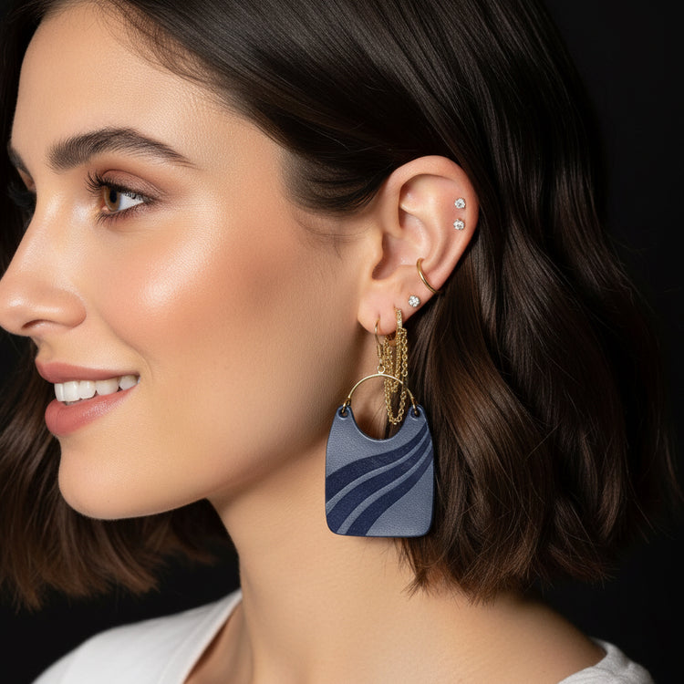 Close-up of an ear wearing blue earrings with a dark background