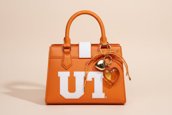 Heart-shaped keychain with orange cord on a beige background