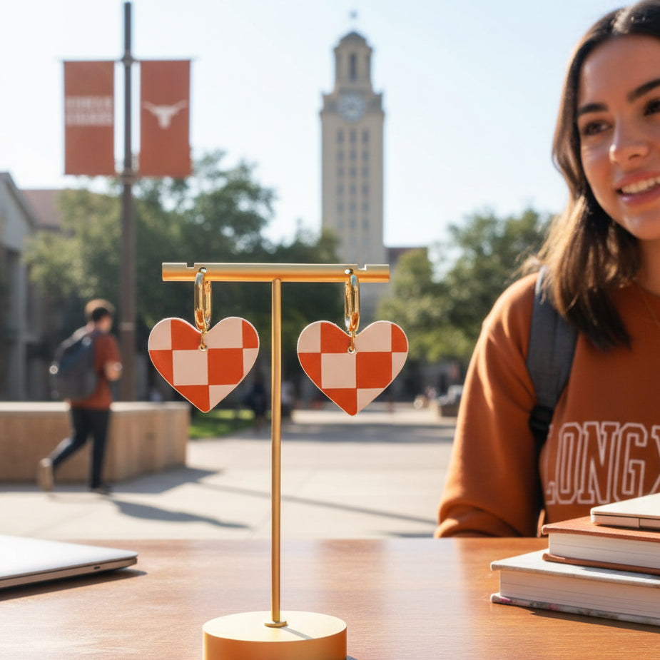 Heart-shaped checkered earrings with gold hoops on a beige background