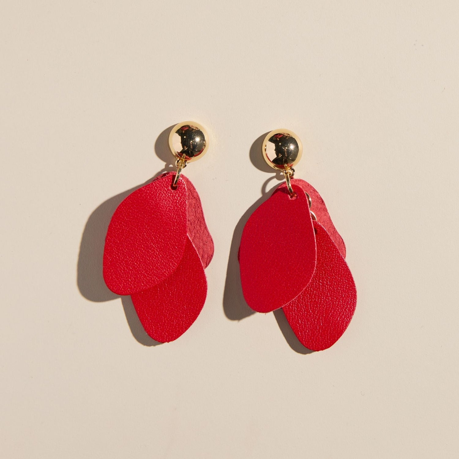 Red earrings with gold accents on a beige background